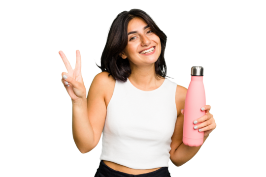 Young Indian woman holding a thermo isolated joyful and carefree showing a peace symbol with fingers.
