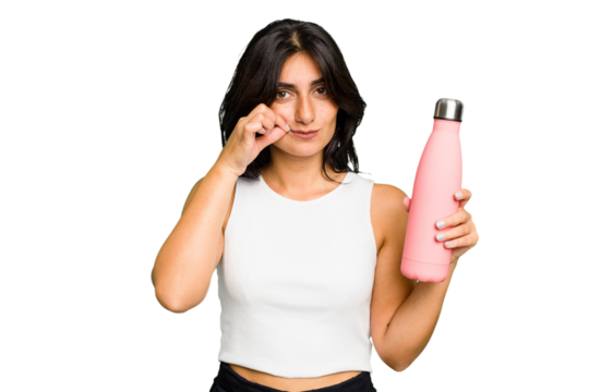 Young Indian woman holding a thermo isolated with fingers on lips keeping a secret.