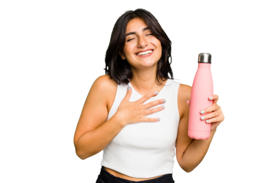 Young Indian woman holding a thermo isolated laughs out loudly keeping hand on chest.