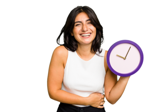 Young Indian woman holding a clock isolated laughing and having fun.