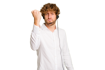 Telemarketer man working with a headset isolated on green chroma background showing fist to camera, aggressive facial expression.