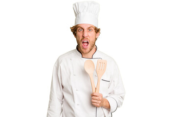 Young cook man isolated on white background screaming very angry and aggressive.