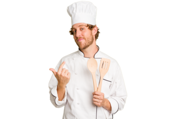 Young cook man isolated on white background pointing with finger at you as if inviting come closer.