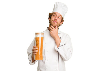 Young cook man isolated on white background looking sideways with doubtful and skeptical expression.