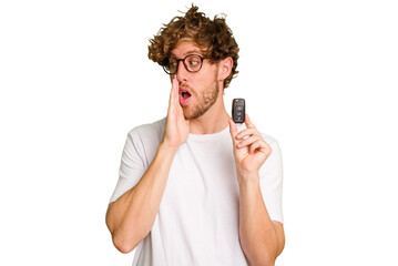 Young caucasian man holding car keys isolated on white background is saying a secret hot braking...