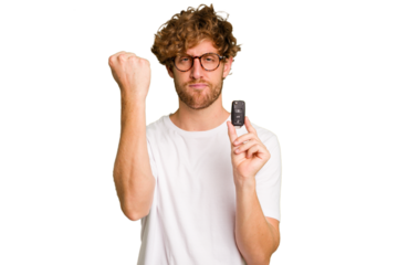 Young caucasian man holding car keys isolated on white background showing fist to camera, aggressive facial expression.