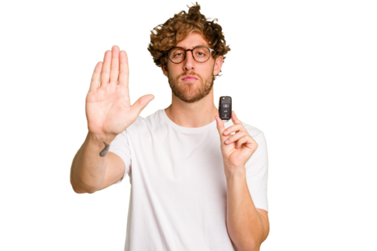 Young caucasian man holding car keys isolated on white background standing with outstretched hand showing stop sign, preventing you.
