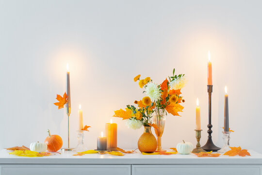 beautiful autumn home decor with burning candles in white interior