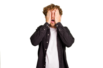 Young caucasian man isolated on green chroma background having fun covering half of face with palm.