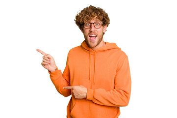 Young caucasian man isolated on green chroma background excited pointing with forefingers away.