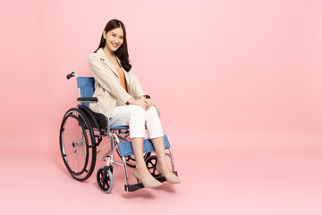 Obraz na płótnie Canvas Young Asian woman sitting on wheelchair isolated on pink background, Personal accident concept