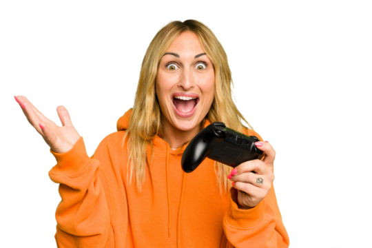Young caucasian gamer woman holding a game controller isolated on green chroma background receiving a pleasant surprise, excited and raising hands.