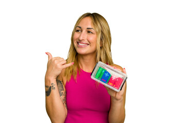 Young caucasian woman holding battery box isolated on green chroma background showing a mobile phone call gesture with fingers.