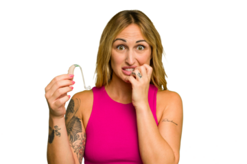 Young caucasian woman wearing hearing aid isolated on green chroma background biting fingernails, nervous and very anxious.