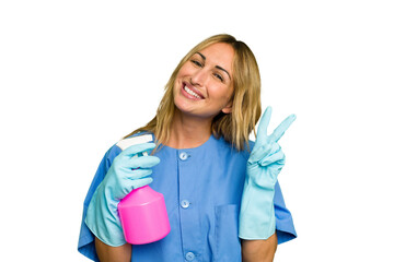 Young cleaner caucasian woman isolated green chroma background joyful and carefree showing a peace...