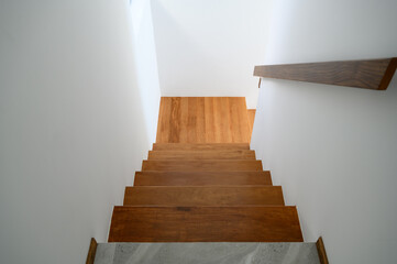 Sunlight on staircase wooden with wooden handrails on white wall in modern home from above....
