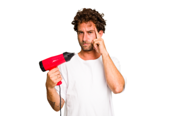 Young caucasian man holding an hairdryer isolated pointing temple with finger, thinking, focused on a task.