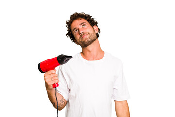 Young caucasian man holding an hairdryer isolated dreaming of achieving goals and purposes