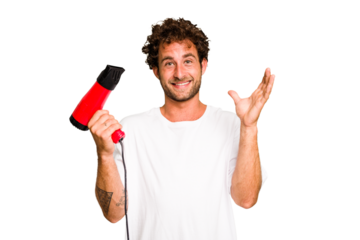 Young caucasian man holding an hairdryer isolated receiving a pleasant surprise, excited and raising hands.