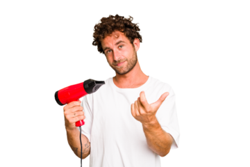 Young caucasian man holding an hairdryer isolated pointing with finger at you as if inviting come closer.