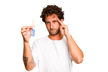 Young caucasian man holding home keys isolated pointing temple with finger, thinking, focused on a task.