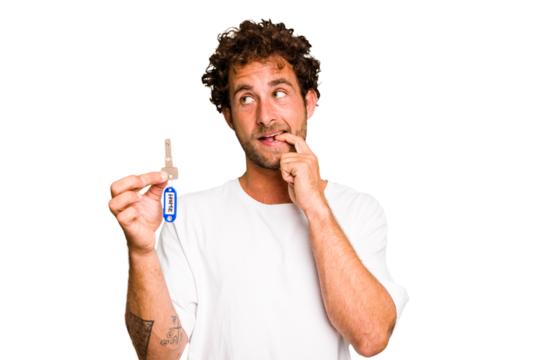 Young caucasian man holding home keys isolated relaxed thinking about something looking at a copy space.