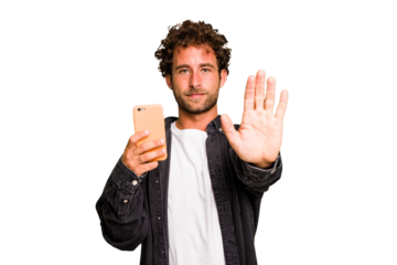 Young caucasian man using mobile phone isolated standing with outstretched hand showing stop sign, preventing you.