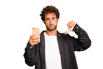 Young caucasian man using mobile phone isolated showing a dislike gesture, thumbs down. Disagreement concept.