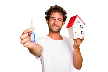 Young caucasian man holding home keys and house model isolated