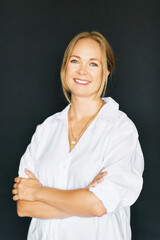 Studio portrait of beautiful confident woman posing on black background, wearing white shirt