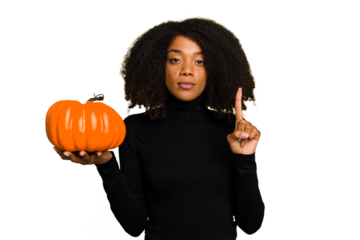 Young African American woman holding a pumpkin for halloween day isolated showing number one with finger.