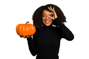 Young African American woman holding a pumpkin for halloween day isolated excited keeping ok gesture on eye.