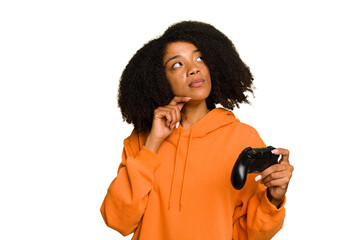 Young African American woman holding a game controller isolated looking sideways with doubtful and skeptical expression. © Asier