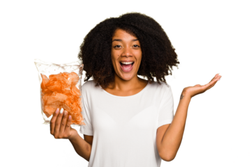 Young African american man holding crips isolated receiving a pleasant surprise, excited and raising hands.