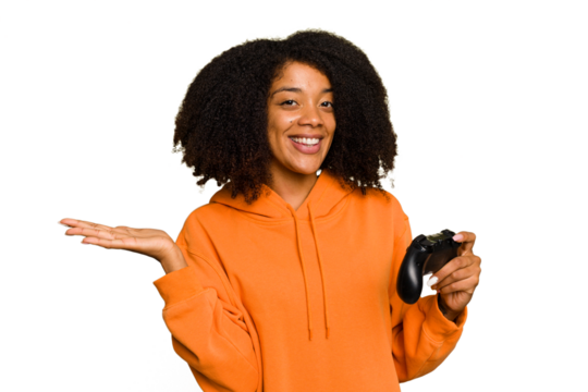 Young African American woman holding a game controller isolated showing a copy space on a palm and holding another hand on waist.