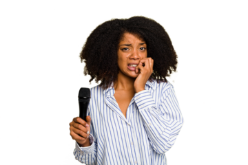 Young African American singer woman holding a microphone isolated biting fingernails, nervous and very anxious.