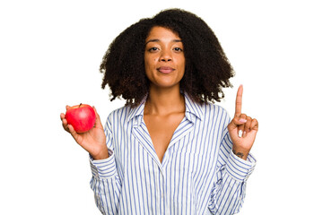 Young African American woman with a red apple isolated showing number one with finger.