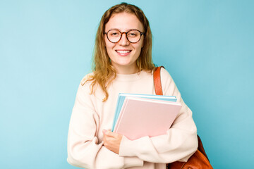 Young student caucasian woman isolated on blue background laughing and having fun.