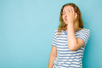 Young caucasian woman isolated on blue background laughing happy, carefree, natural emotion.