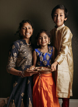 A Diwali portrait of three kids indoors dressed in Indian attire 