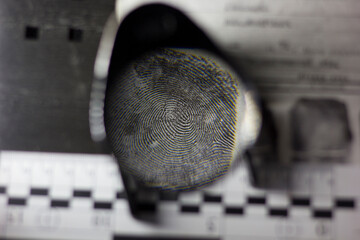 Lens, fingerprints and forensic ruler on fingerprint card