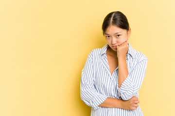 Fototapeta premium Young Asian woman isolated on yellow background who feels sad and pensive, looking at copy space.