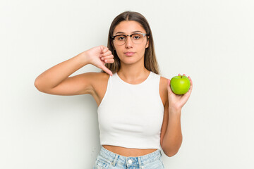 Young Indian woman holding an apple isolated on white background showing a dislike gesture, thumbs down. Disagreement concept.