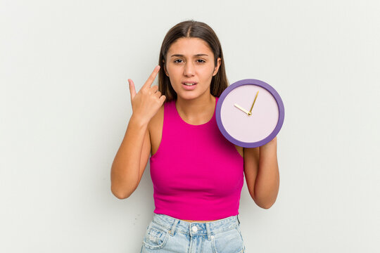 Young Indian woman holding a clock isolated on white background showing a disappointment gesture with forefinger.