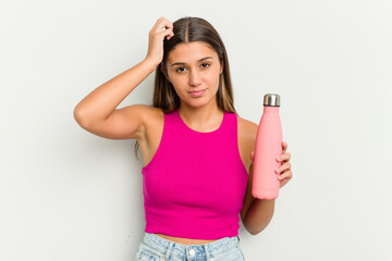 Young indian woman holding a pink thermo isolated on white background being shocked, she has...