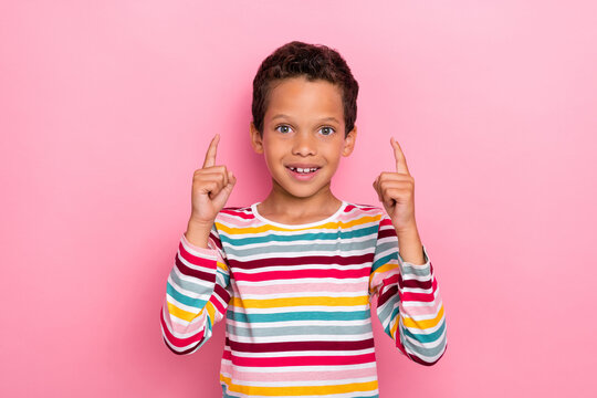 Photo portrait of handsome little hispanic boy point up empty space smiling wear stylish striped outfit isolated on pink color background