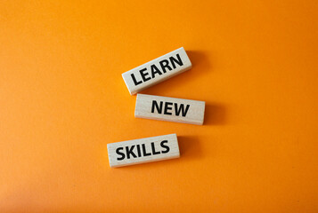 Learn new skills symbol. Concept words Learn new skills on wooden blocks. Beautiful orange background. Business and Learn new skills concept. Copy space.
