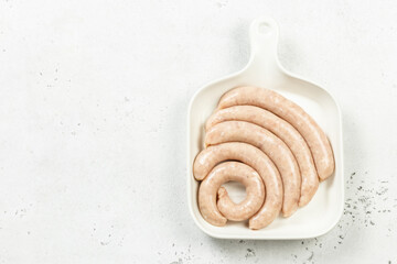 Barbecue raw sausages on white plate. Top view, copy space.