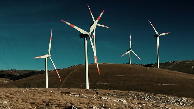 A wind farm or wind park at sunset located in the mountains of Italy Europe and it allows to realize clean energy. It&rsquo;s sustainable, renewable energy for enviromental