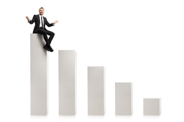 Fototapeta premium Cheerful businessman sitting on a bar chart column and smiling at camera